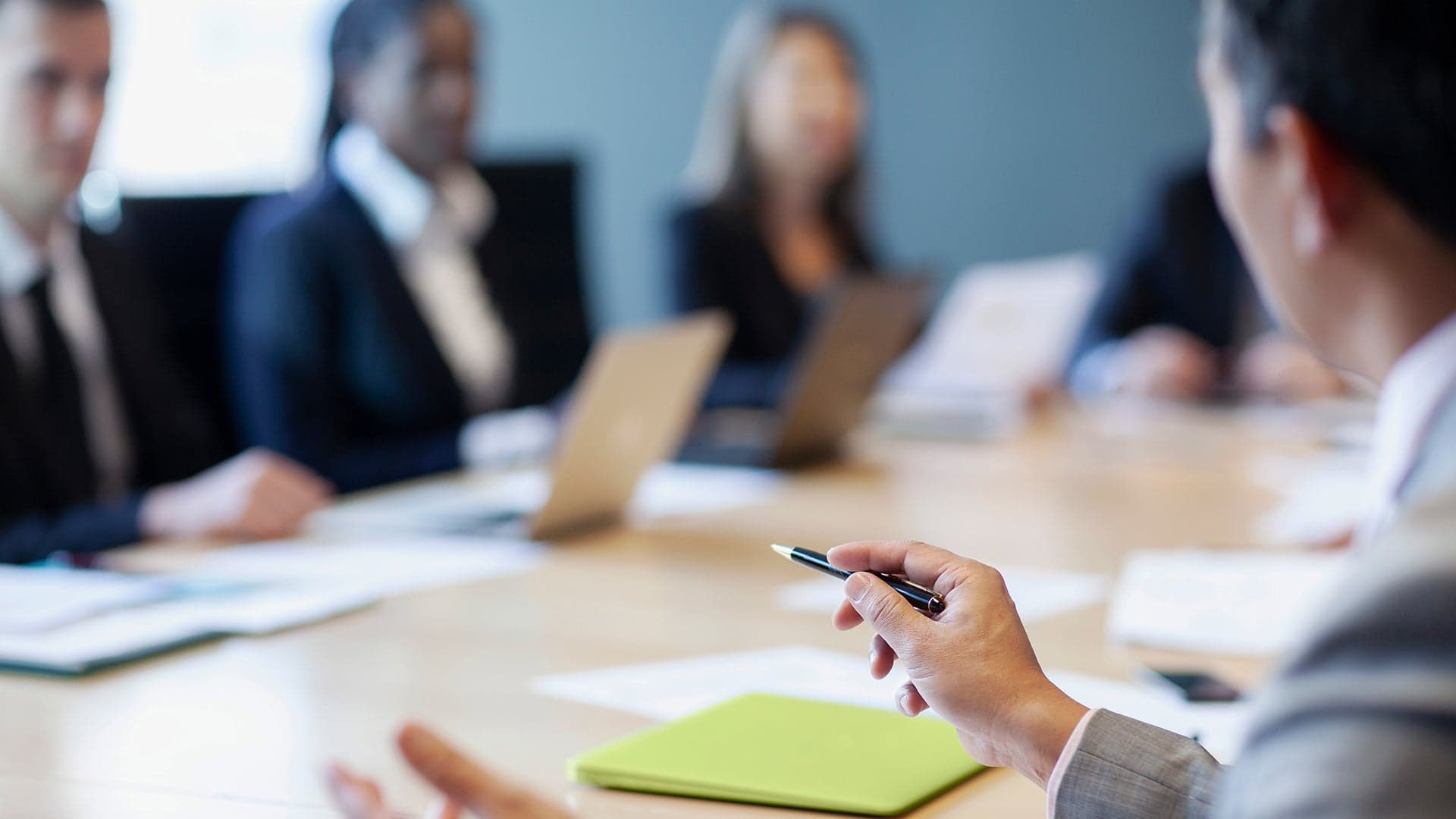 People in a board room with a man holding a pen.